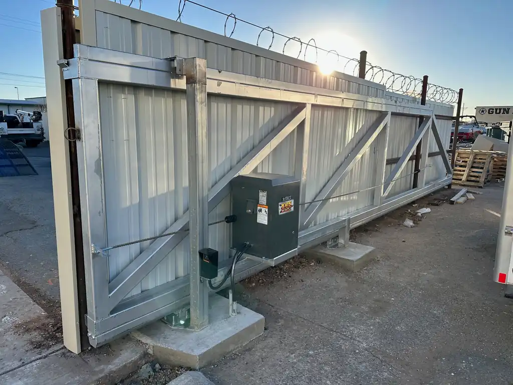 Heavy galvanized industrial cantilever slide gate with corrugated infill and a DKS operator, razor wire above